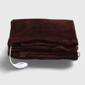 Couverture Chauffante Nomade beige pliée sur lit, prête pour un confort optimal en voyage. Idéale accessoires chauffants.